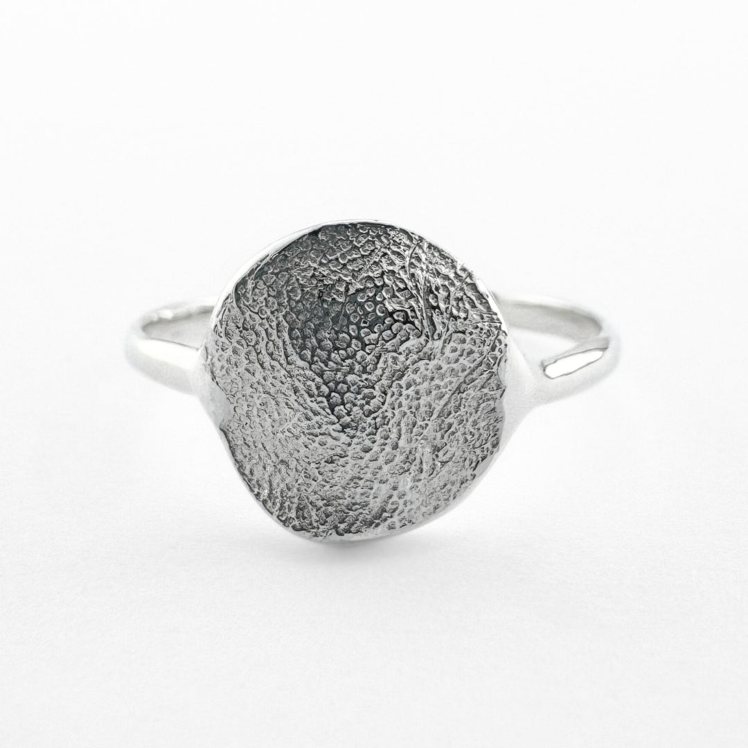 Silver paw print impression ring on light grey background