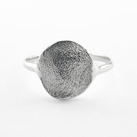 Silver paw print impression ring on light grey background