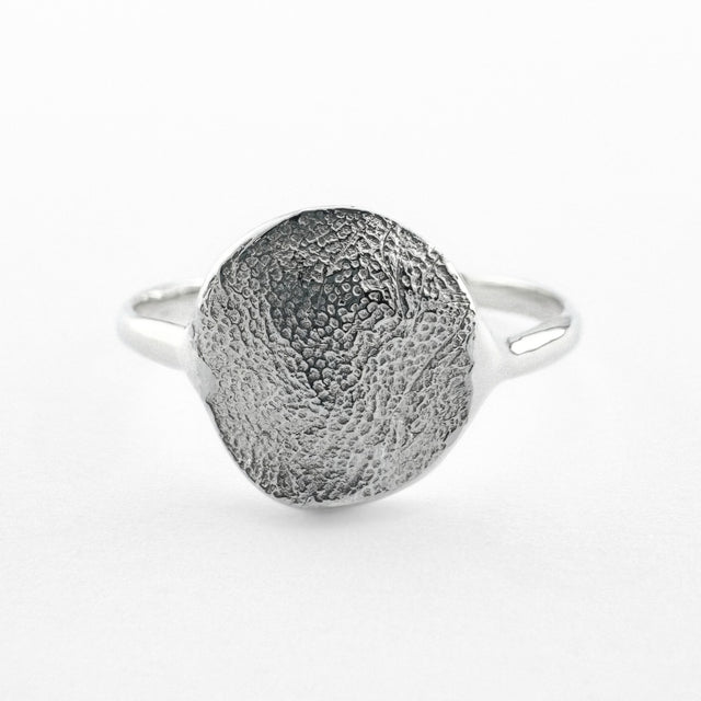 Silver paw print impression ring on light grey background