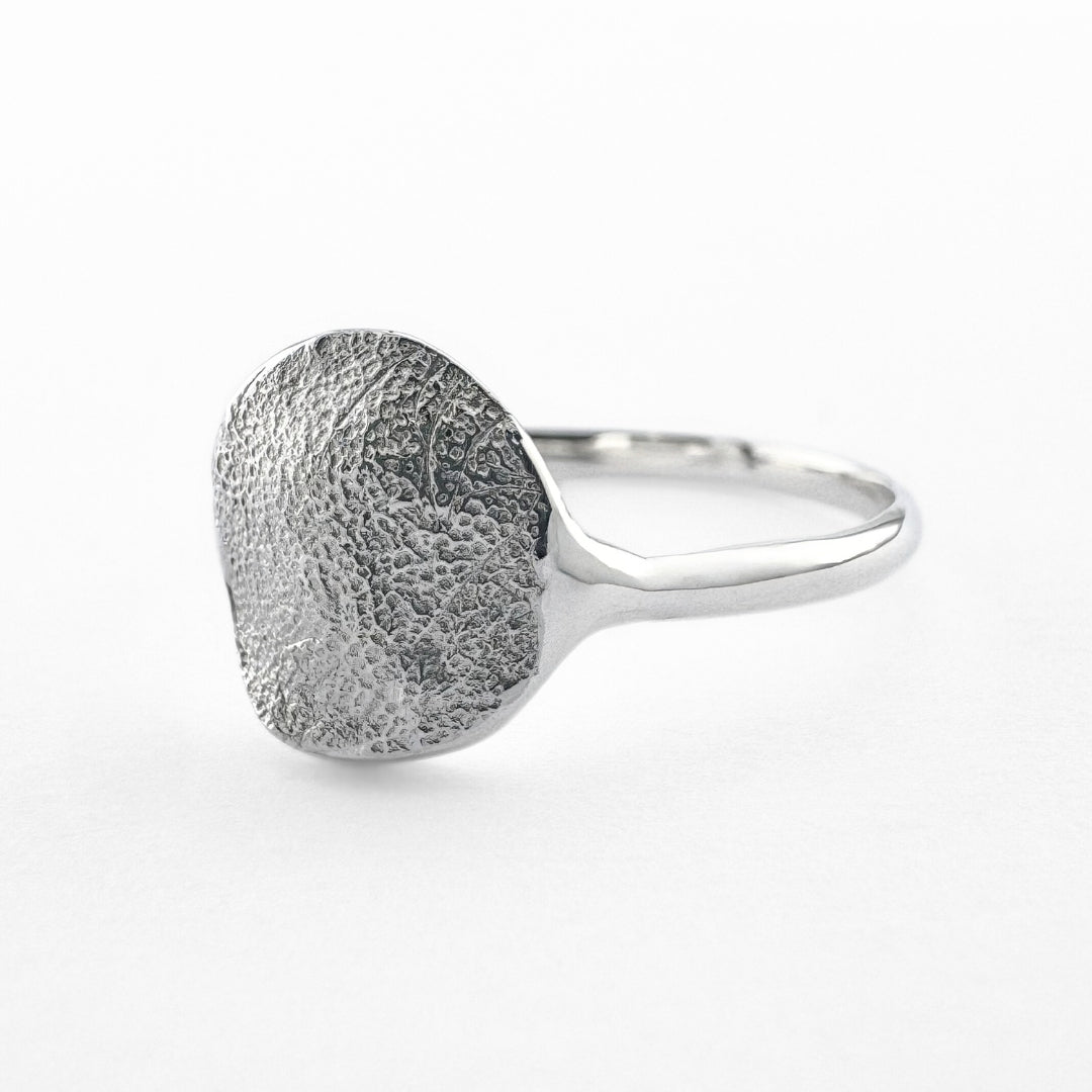 Silver paw print impression ring on light grey background