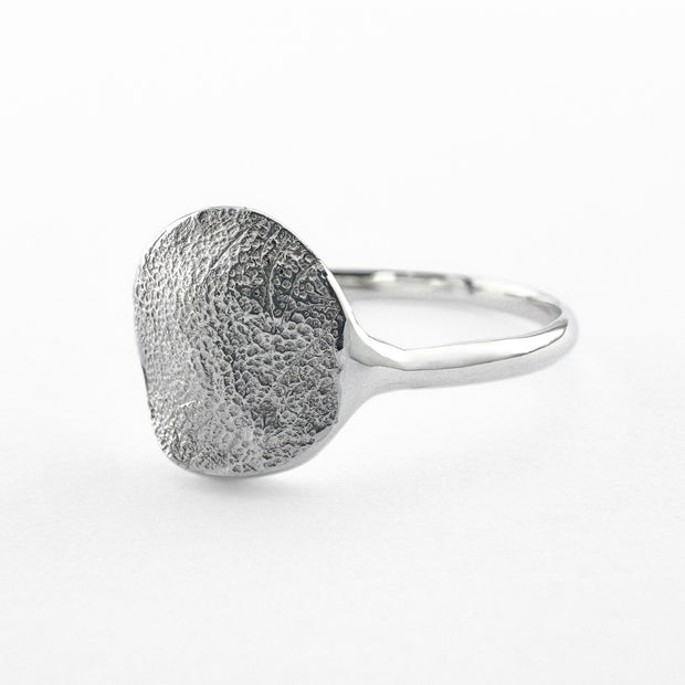 Silver paw print impression ring on light grey background