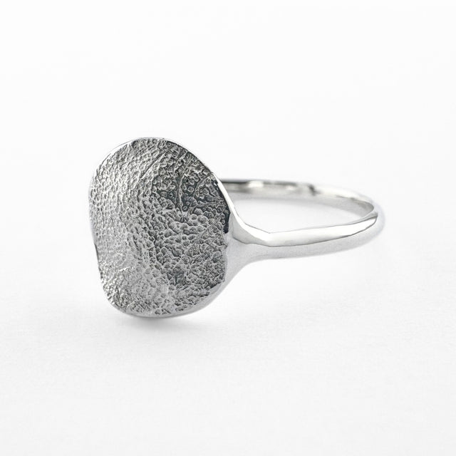 Silver paw print impression ring on light grey background