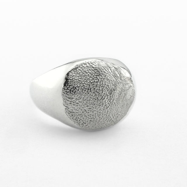 Silver paw print impression signet ring on light grey background