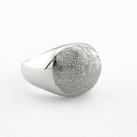 Silver paw print impression signet ring on light grey background
