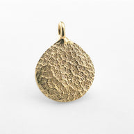 Close up of gold dogs nose print pendant on light grey background