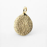 Close up of gold dogs nose print pendant on light grey background