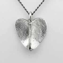 Silver heart-shaped pendant with fingerprint impressions against a light grey background