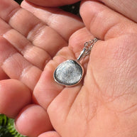 Close up of silver fingerprint pendant on a childs hands