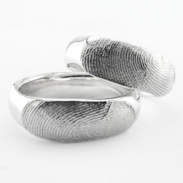 Two sterling silver fingerprint ring bands on light grey background