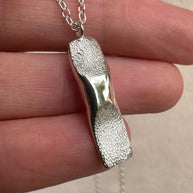 Close up of silver pendant with two dogs nose prints