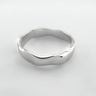 Silver ring with a wave design on a light grey background