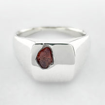 Silver signet ring with an orange sapphire on a white background