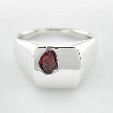 Silver signet ring with an orange sapphire on a white background