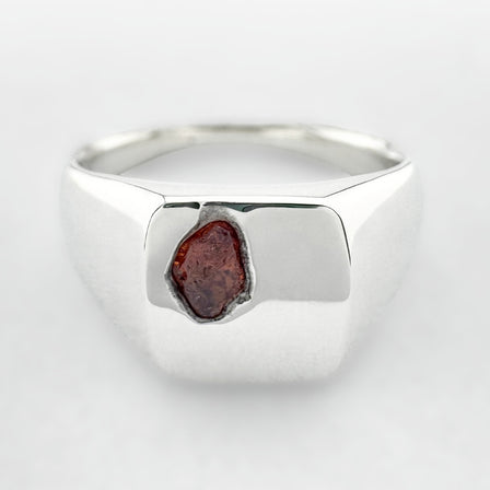 Silver signet ring with an orange sapphire on a white background
