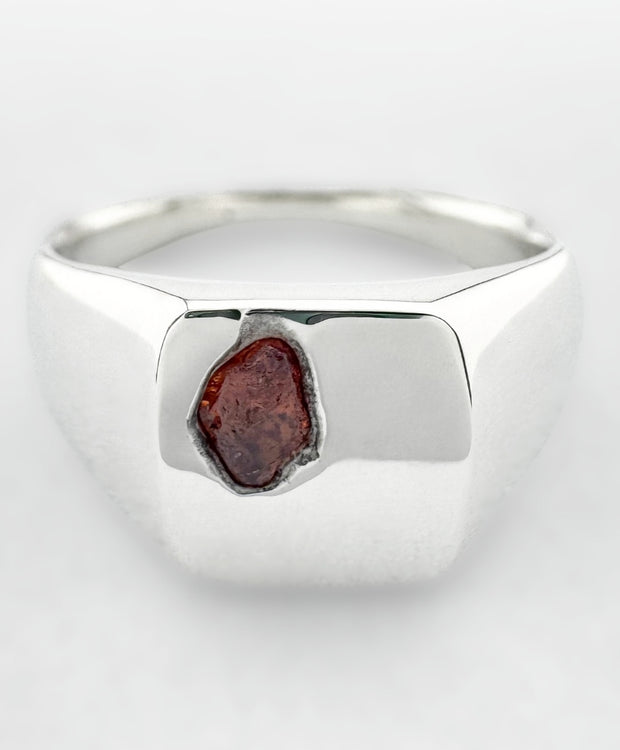 Silver signet ring with an orange sapphire on a white background