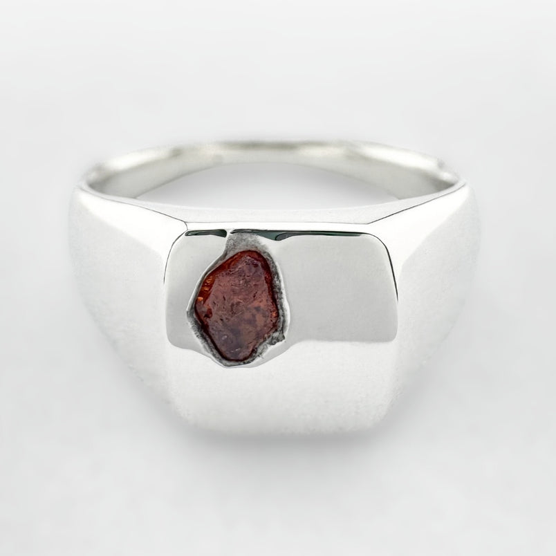 Silver signet ring with an orange sapphire on a white background