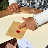 Closeup of child pressing her finger into a red ball of wax