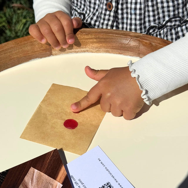 Closeup of child pressing her finger into a red ball of wax