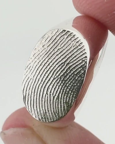 Close up of silver fingerprint signet ring on light grey background